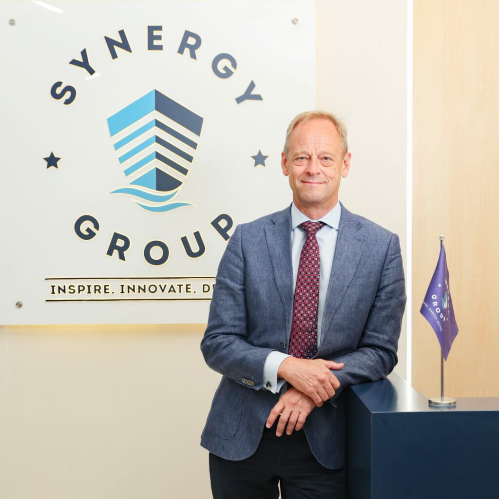 Jesper Kristensen, Group CEO of Synergy Marine Group, photographed in front of a wall featuring the company logo