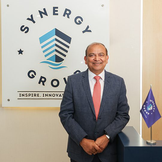 Synergy Marine Groupの共同CEOであるアジェイ・チョードリーが、会社のロゴを掲げてSynergyオフィスのレセプションに出席。