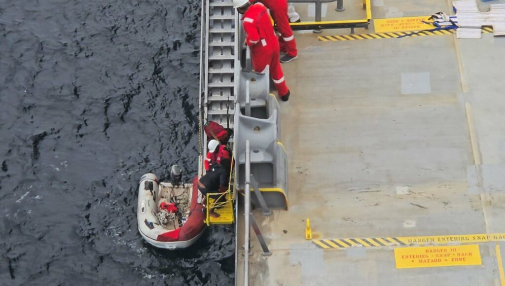 Crew of GLOBE POLARIS assisting the rescued sailor from a dinghy during the rescue operation in the Caribbean Sea.