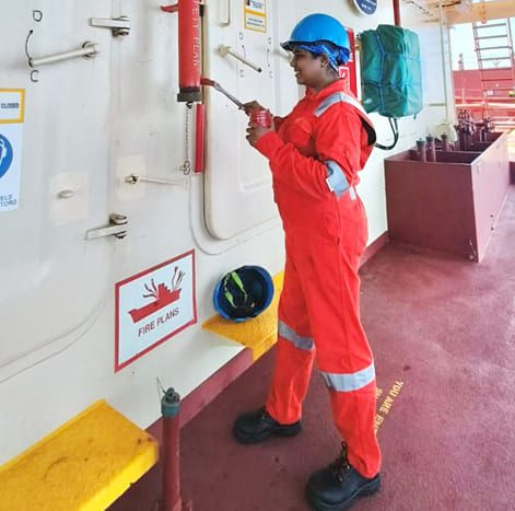 Third Officer Sakshi Singh inspecting a piece of safety equipment mounted on a wall